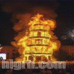 Crowds gathered in Valencia during the Fallas Festival in Valencia watching a large monument burning with fireworks in the background.