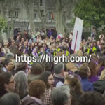 A real photo of a large crowd during the Spain protests today with the website link higrh.com in the center.