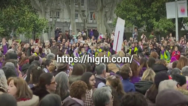 A real photo of a large crowd during the Spain protests today with the website link higrh.com in the center.