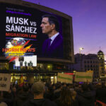 Elon Musk and Pedro Sánchez on a digital billboard in Madrid debating Spain migration law with protesters holding signs.